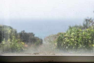Ocean-facing home window with visible coastal haze and residue on the exterior glass