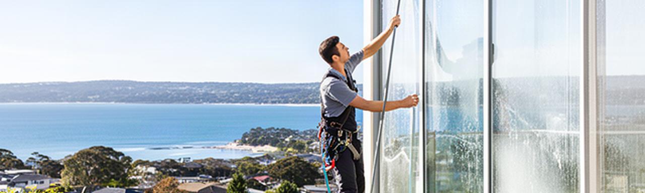 Window cleaner working on a bright Newcastle home with a view across the local coastline